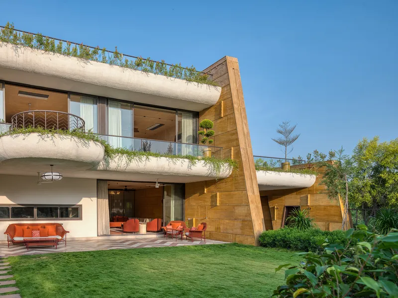 Garden facade with curved planted balconies and angled stone-clad panels framing the glass openings