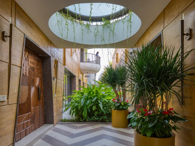 Interior courtyard with circular skylight ringed by trailing vines above planters and chevron paving