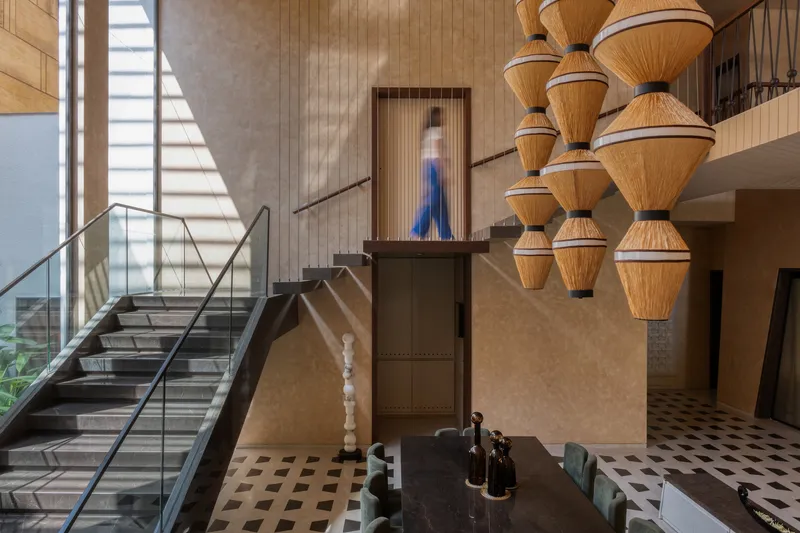 Mezzanine view showing steel staircase, timber wall cladding, and clustered pendant lights with a figure ascending