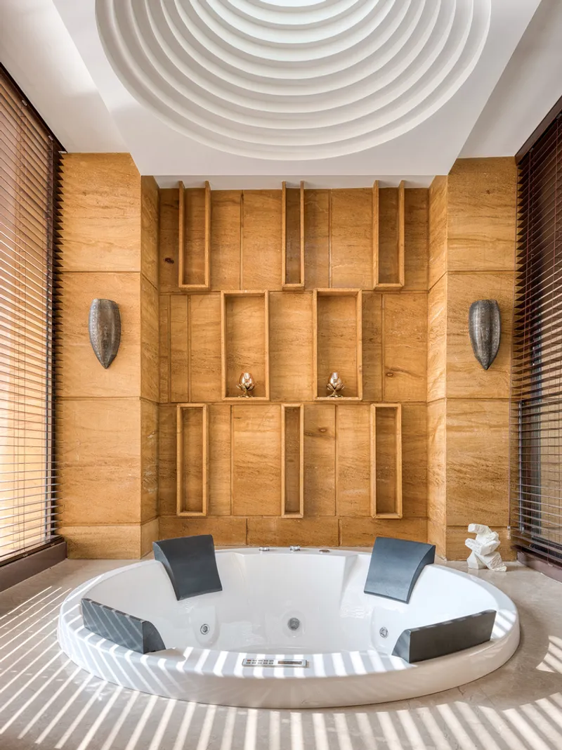 Bathtub alcove with concentric plaster ceiling rings and paneled teak wall featuring recessed niches