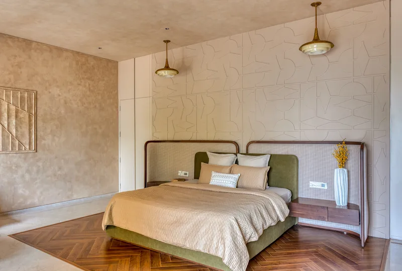Bedroom with herringbone timber floor, textured wall panels and brass pendant lights above the headboard