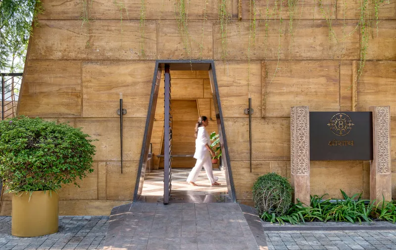 Tapered entry portal with studded door as a person walks through in sunlight