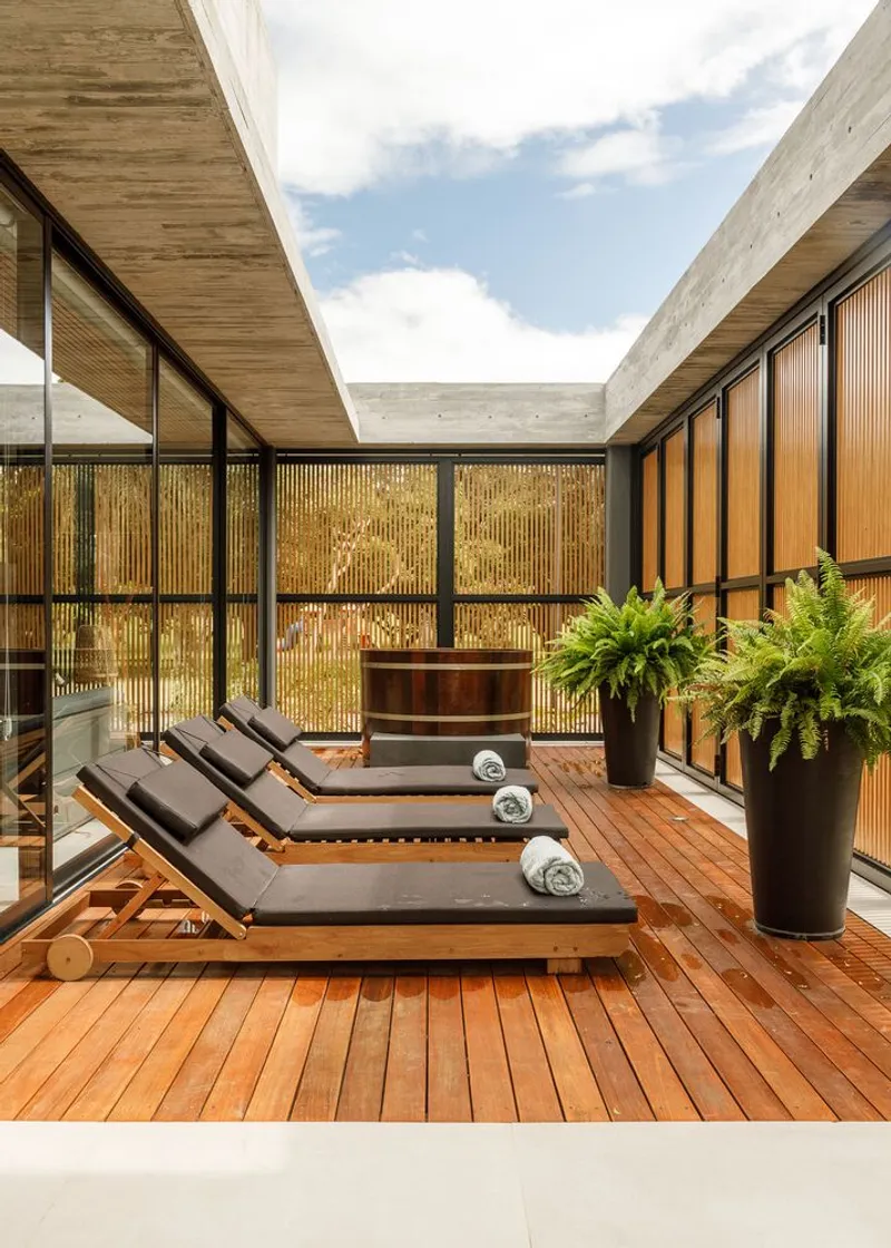 Interior courtyard with timber decking, loungers, and vertical timber screens under open sky