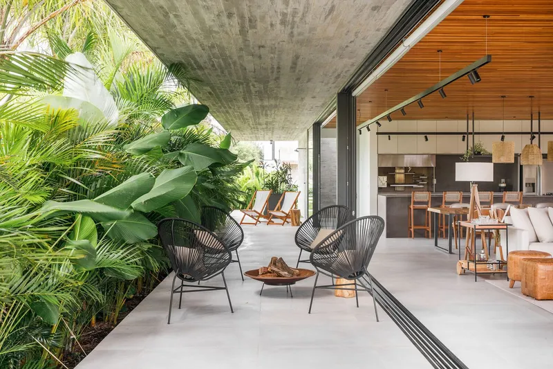 Covered terrace with board-formed concrete soffit opening to dining area surrounded by tropical plantings