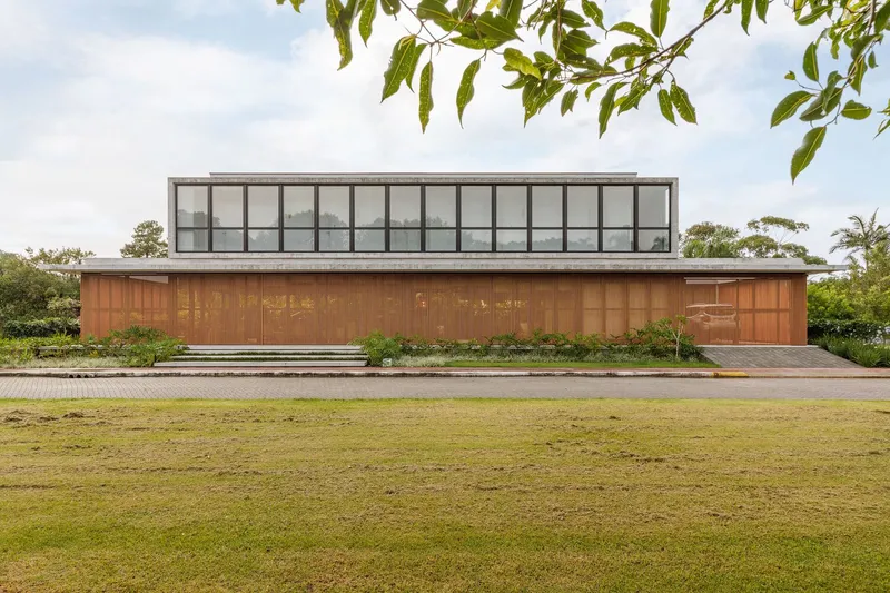Street elevation showing the vertical timber facade below a glazed upper volume and expansive lawn