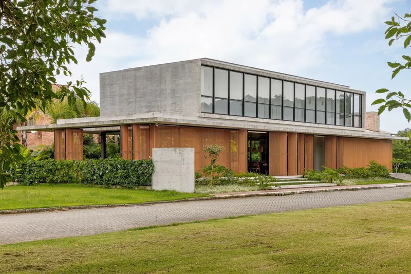 Corner view of the glazed upper box and timber-screened ground floor with concrete entry wall