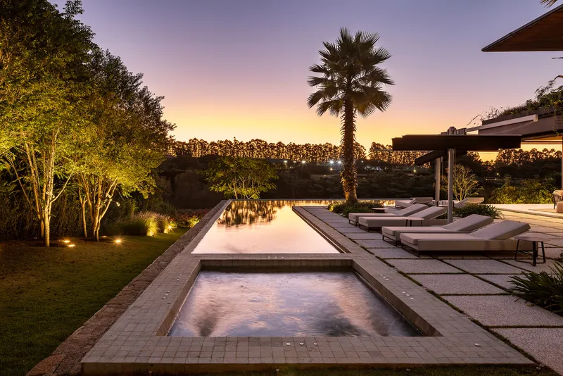 Pool terrace with loungers and palm tree silhouetted against sunset sky