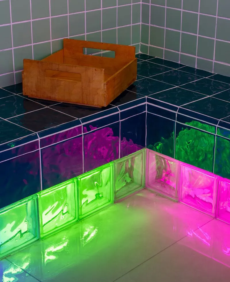 Corner detail of glass block wall with gradient colored light and wooden crate on counter