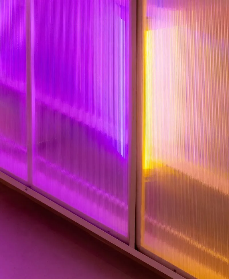 Close-up of translucent polycarbonate wall panels illuminated in magenta and orange light
