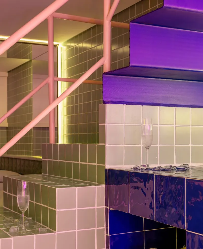 Close-up of tiled steps and pink metal railing with wine glasses set on the stair treads