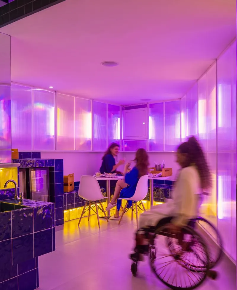 Dining area with translucent backlit panels and figures gathered around a table as one cycles past