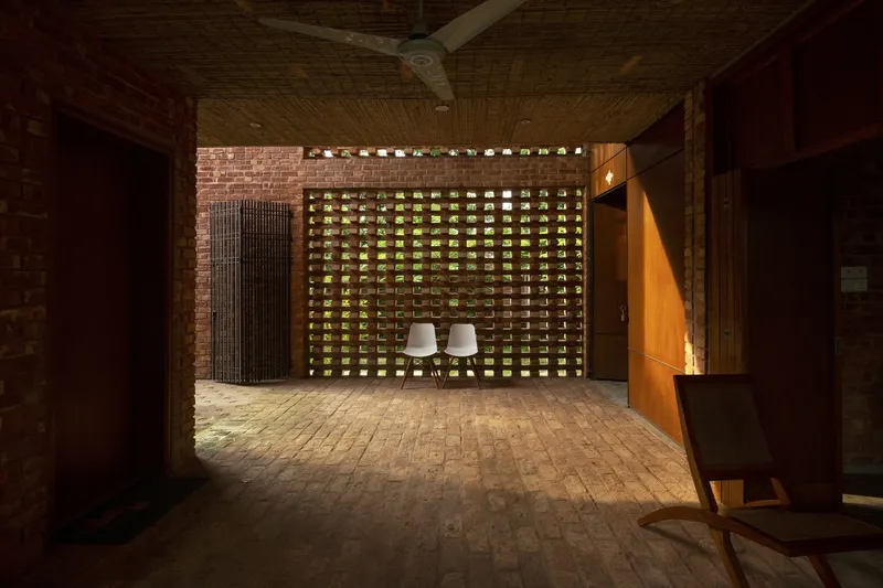 Brick-paved terrace with perforated brick screen wall filtering evening light into the seating area