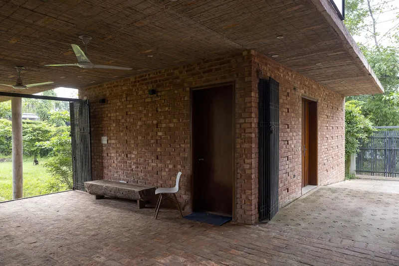 Covered terrace with exposed brick walls, timber ceiling and a single chair by an open doorway