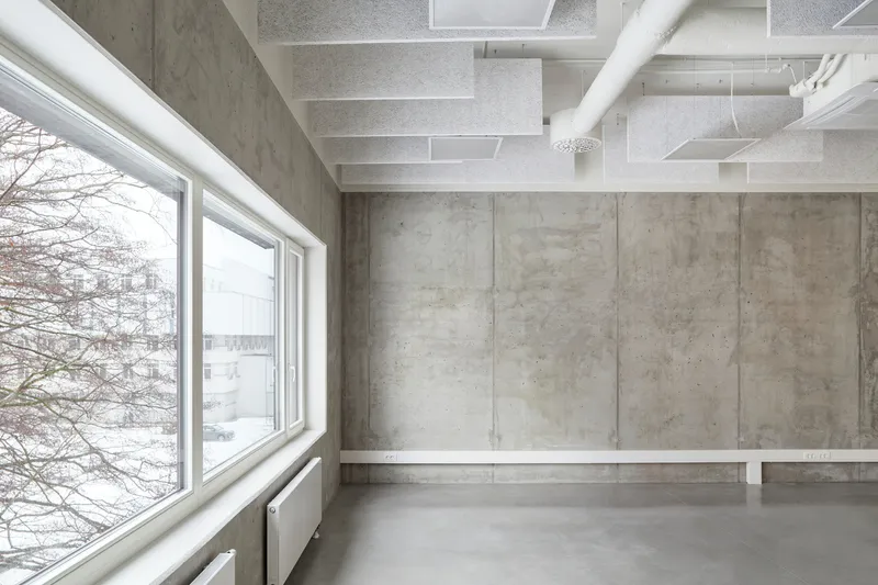 Concrete interior room with polished floor and window overlooking bare winter trees