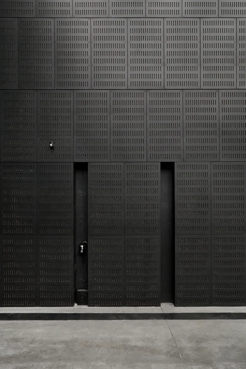 Perforated black metal double door centered in a grid of acoustic panels