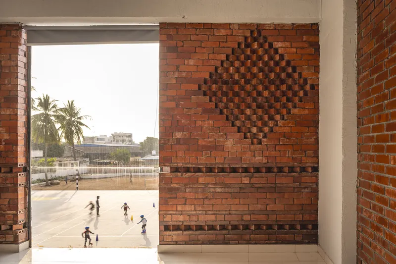 Interior corridor framing a diamond brick pattern wall with a view to the courtyard beyond