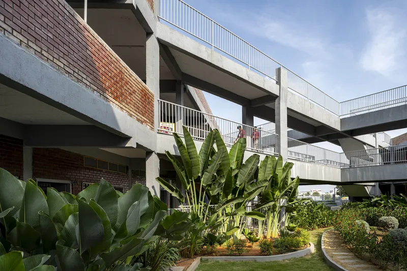 Concrete circulation bridges spanning across a landscaped courtyard garden with banana plants and lawn beds