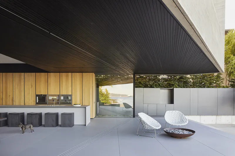 Covered terrace with timber kitchen cabinetry and ribbed soffit under concrete overhang