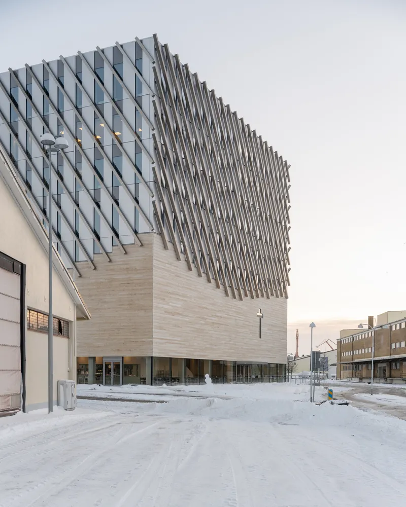 Angled view of the faceted glass volume cantilevering over the timber base in frozen plaza