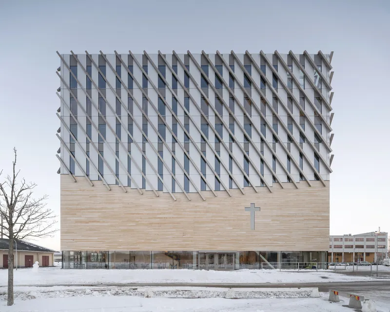 Front elevation showing the cross symbol on timber wall beneath the repeating glass louver facade