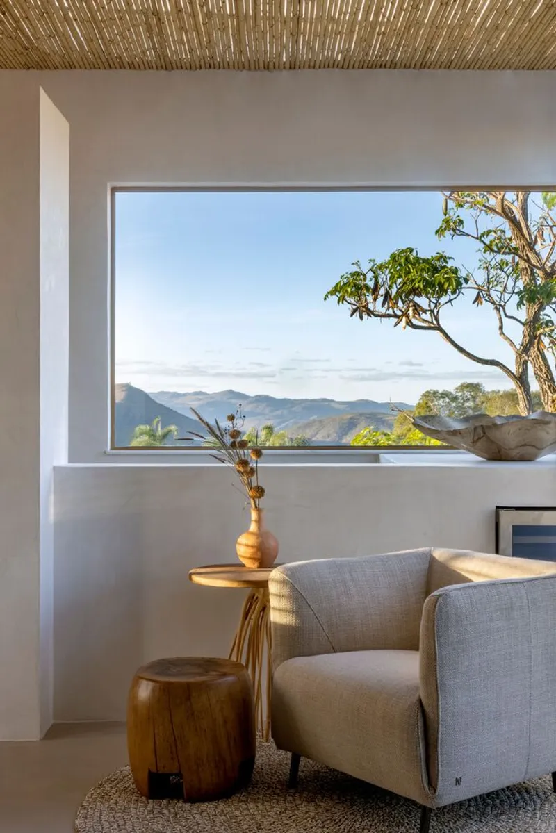 Interior corner with horizontal window framing mountain views and woven reed ceiling overhead