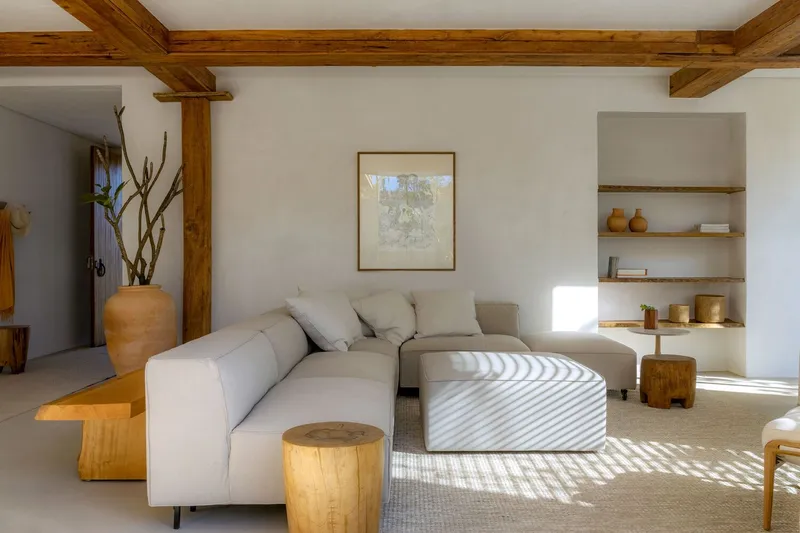 Living room with exposed timber beams and sunlight striped across the floor through unseen aperture