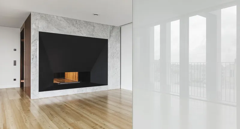 Living room with marble fireplace surround and tall white curtained windows filtering natural light