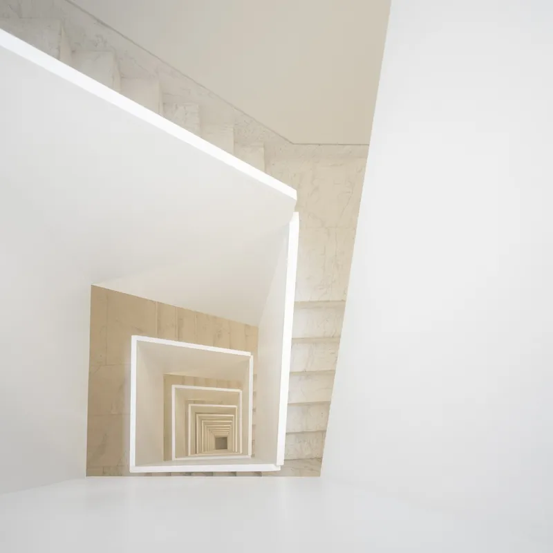 Looking up through a square stone stairwell creating a receding frame perspective