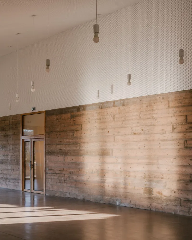 Reclaimed timber plank wall with small window opening and suspended pendant lamps above