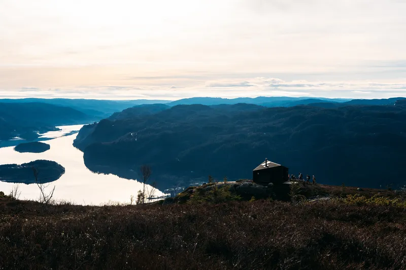 Silhouetted refuge on a hilltop above winding lake inlets at dusk