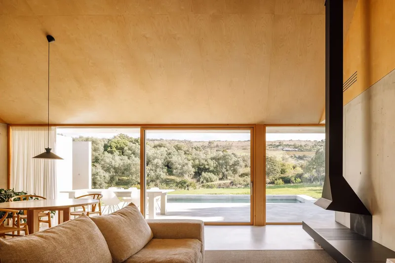 Living room with full-height glazing framing views of olive groves and rolling countryside beyond