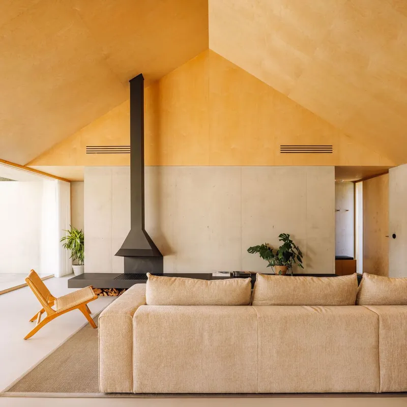 Living room with suspended black fireplace beneath a plywood gabled ceiling and linear vents
