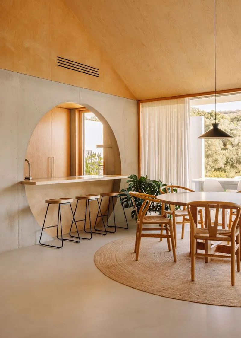 Dining area with circular arched kitchen niche and floor-to-ceiling windows overlooking olive trees