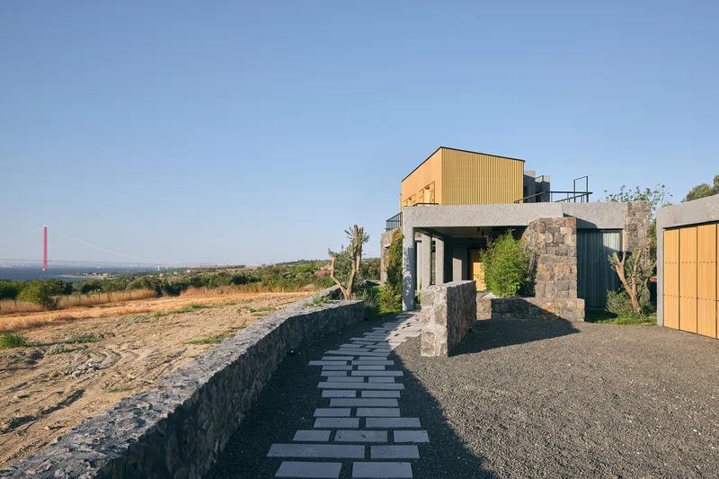 Stone paved entry path leading to the stone and timber volume set among vineyards at dusk
