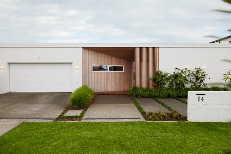 Entry driveway with concrete pavers in grass strips leading to timber-clad facade