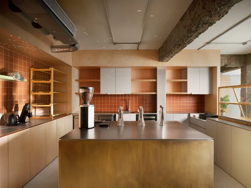 Kitchen with brass island, terracotta tile backsplash and exposed concrete beam overhead