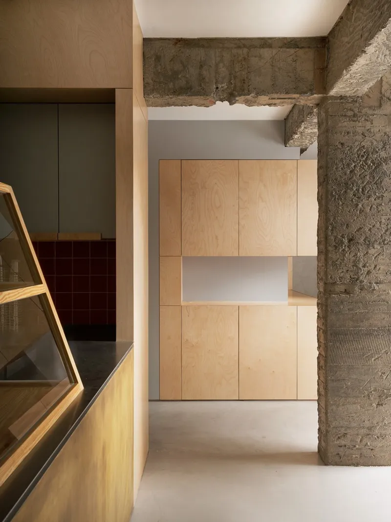 Passage showing exposed concrete beams framing plywood built-in cabinetry