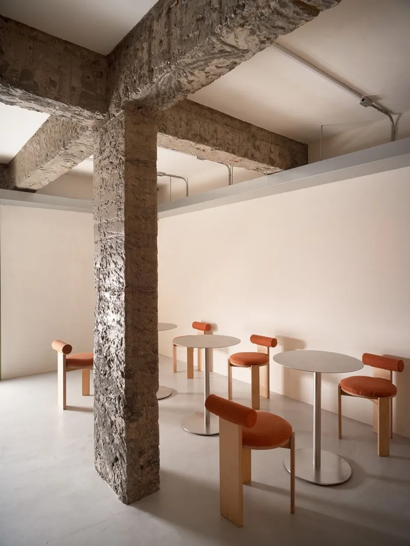 Dining area with orange upholstered stools beneath exposed stone beams and plastered ceiling