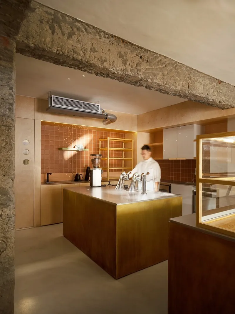 Service counter with orange tile backsplash beneath exposed concrete beam and steel ductwork
