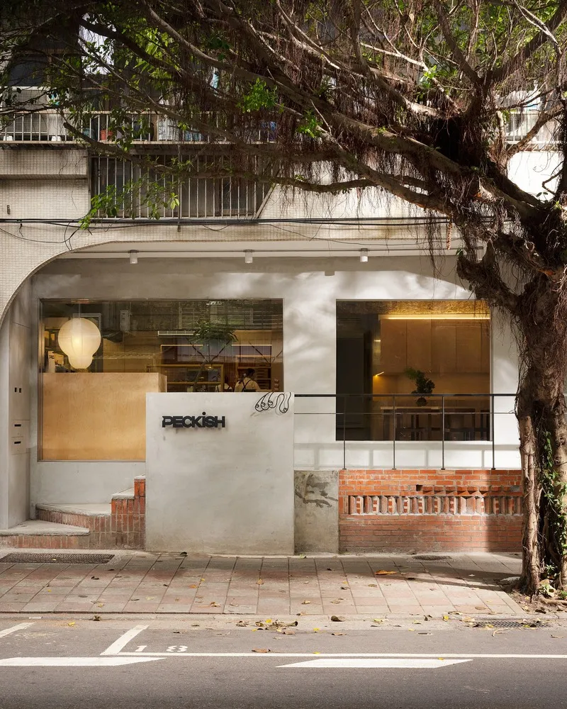 Street facade with arched entry and overhanging tree casting shadows on the sidewalk