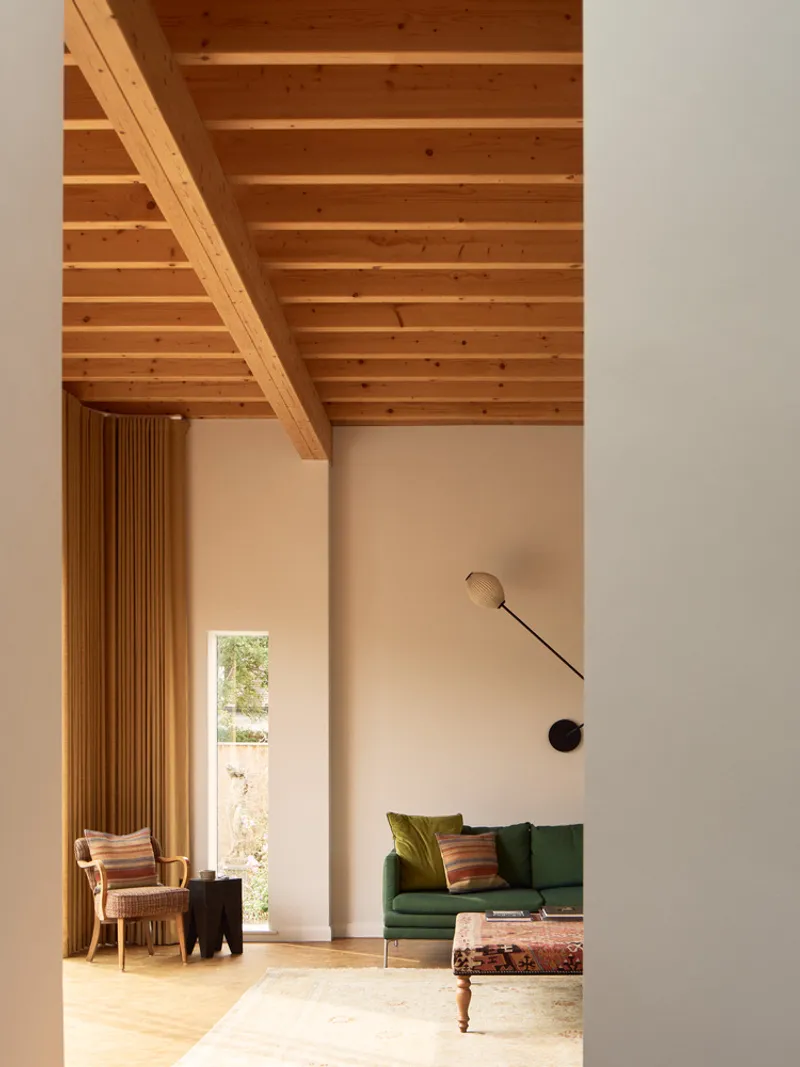 Interior view showing exposed timber beam ceiling and vertical wooden slat partition alongside a cream wall