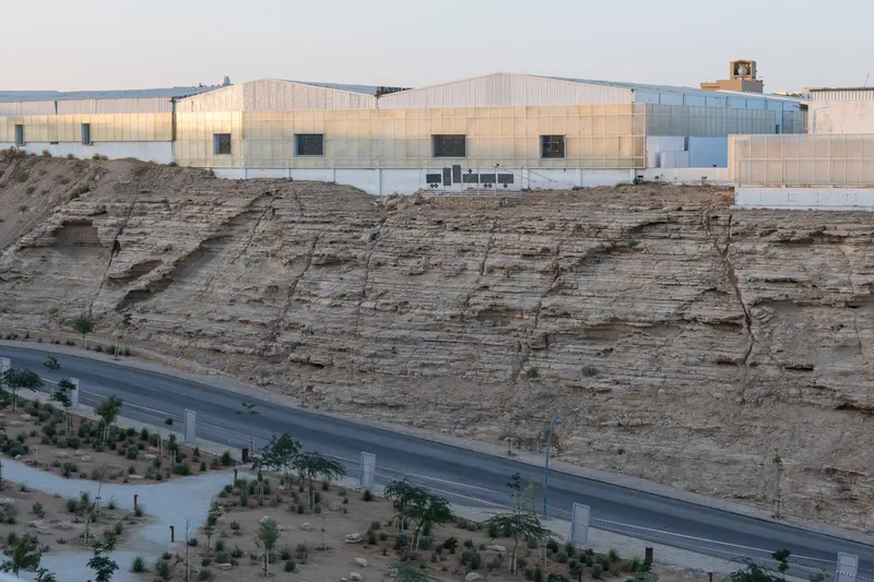 Building atop a sandstone cliff edge above a road lined with newly planted trees