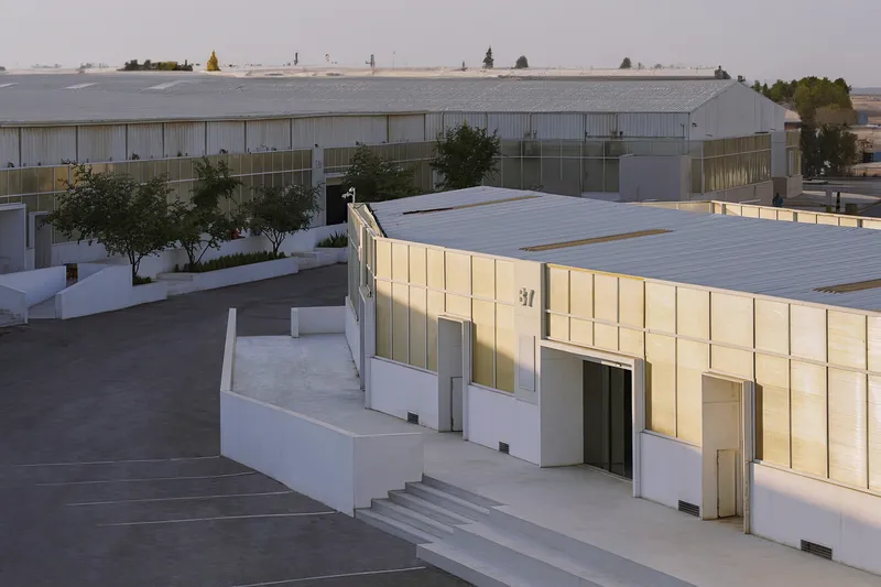 Courtyard view of the white-walled entry pavilion with glowing paneled facade at twilight