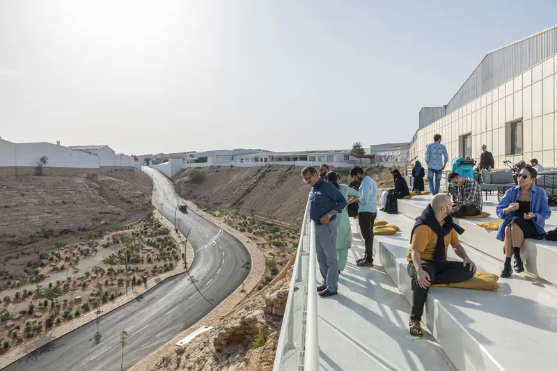Rooftop terrace overlooking a curving drainage canal with planted embankments and seated visitors
