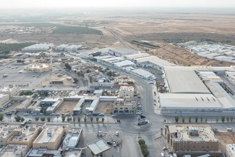 Aerial view of industrial compound with metal-roofed warehouses beside roads and arid landscape