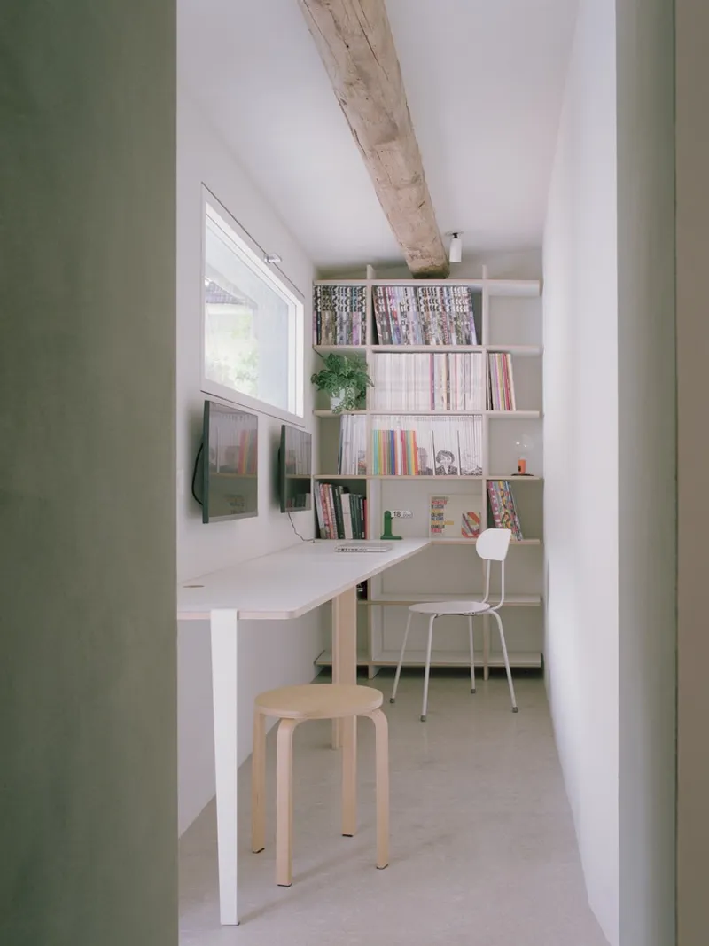 Study alcove viewed through a doorway with built-in desk, bookshelves, and an exposed timber beam overhead