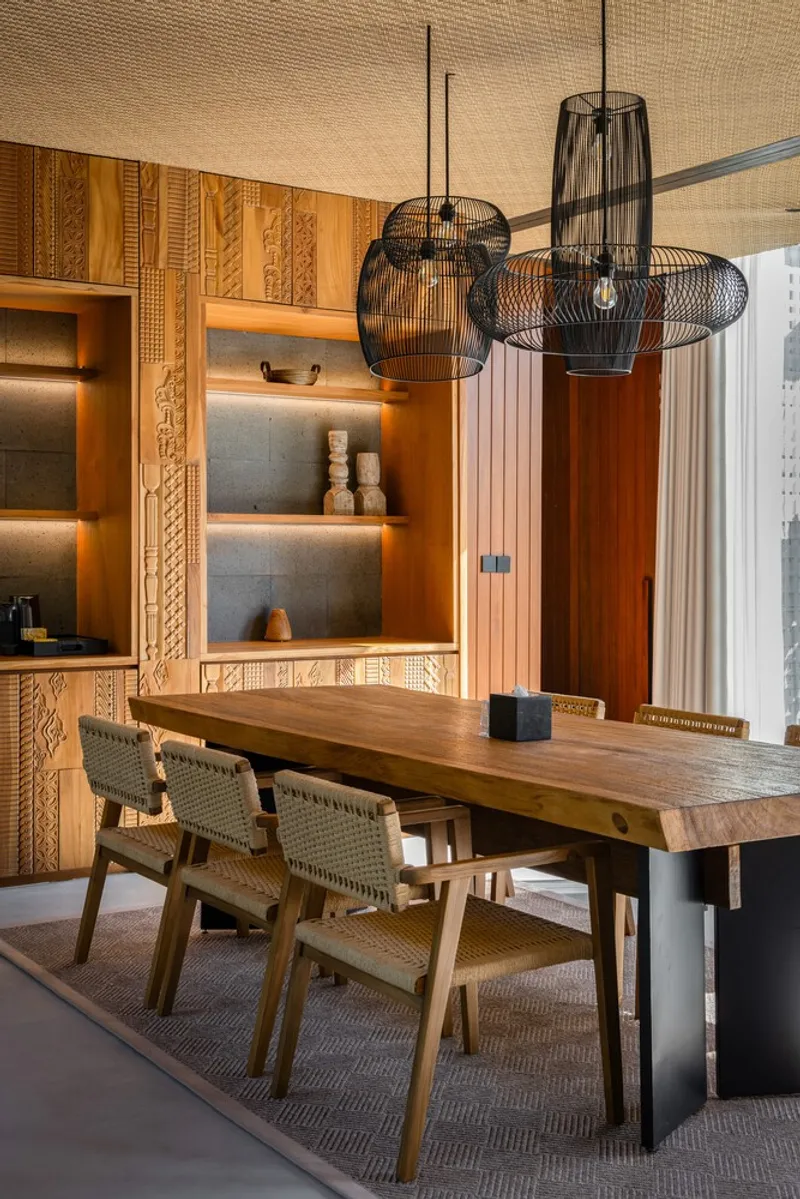 Dining area with wire pendant lights above timber table and carved wood millwork wall panels