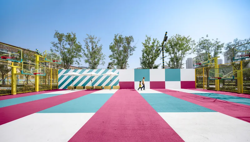 Painted sports court with pink and turquoise stripes leading to white wall with diagonal pattern