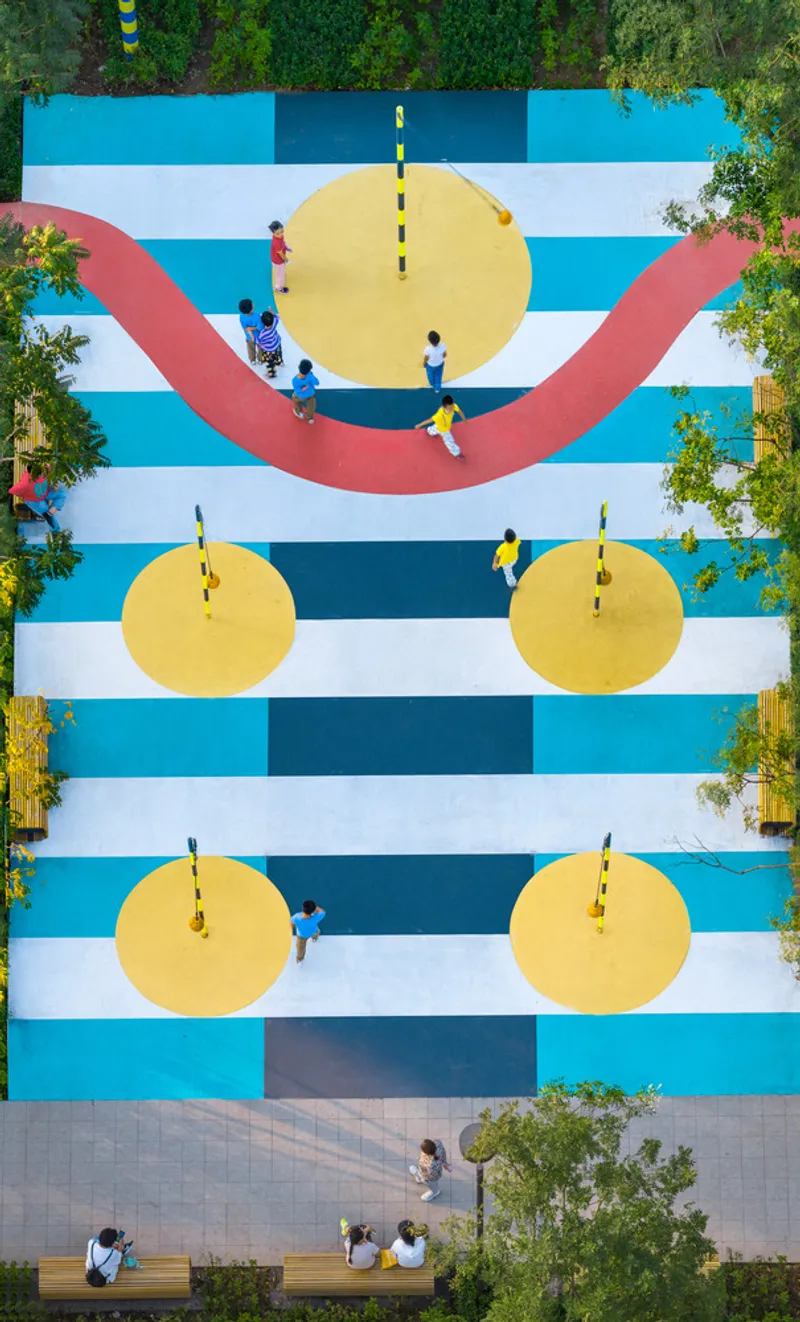 Aerial view of painted court with blue stripes, yellow circles and pink arc with people gathered