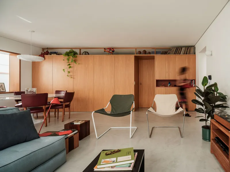 Living room with floor-to-ceiling oak cabinetry and a person moving past the built-in shelving